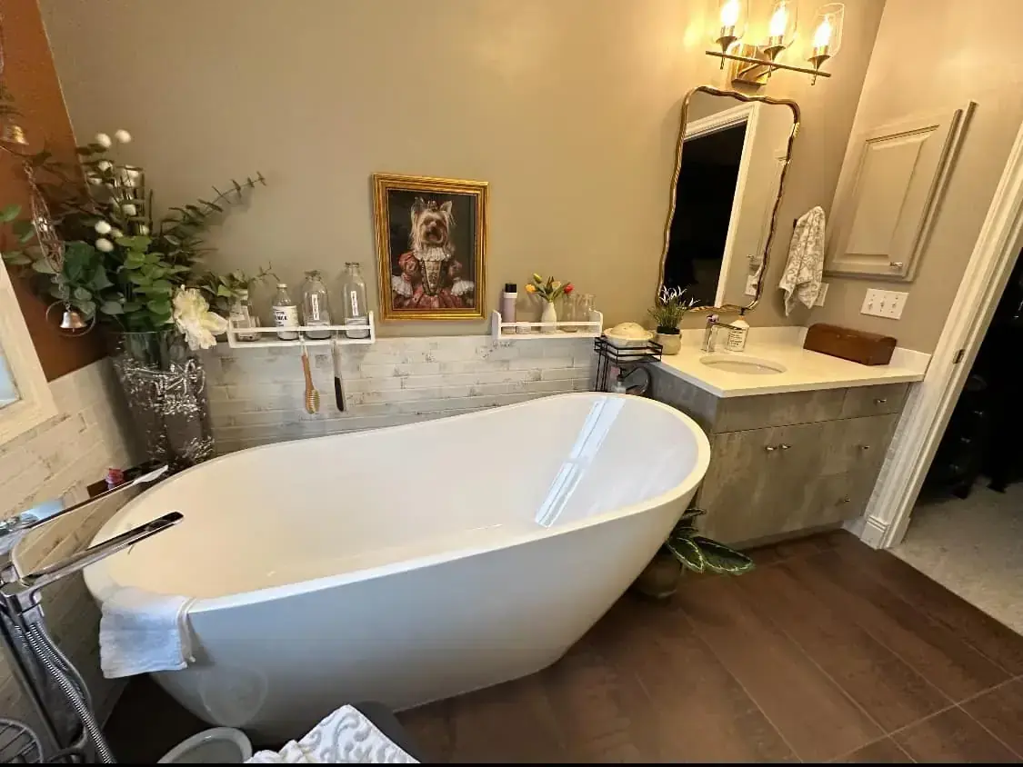 Modern bathroom with freestanding tub, vanity, gold-framed mirror, and subway tile in Calgary