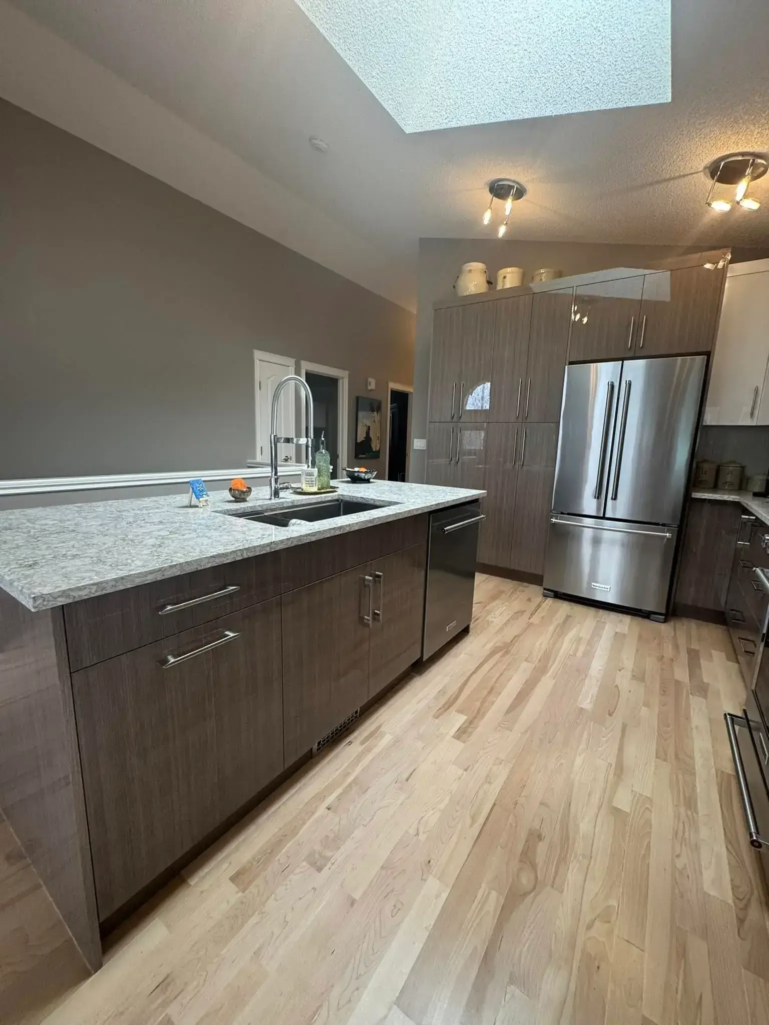 Modern kitchen renovation with white shaker cabinets, quartz countertops, and stainless appliances